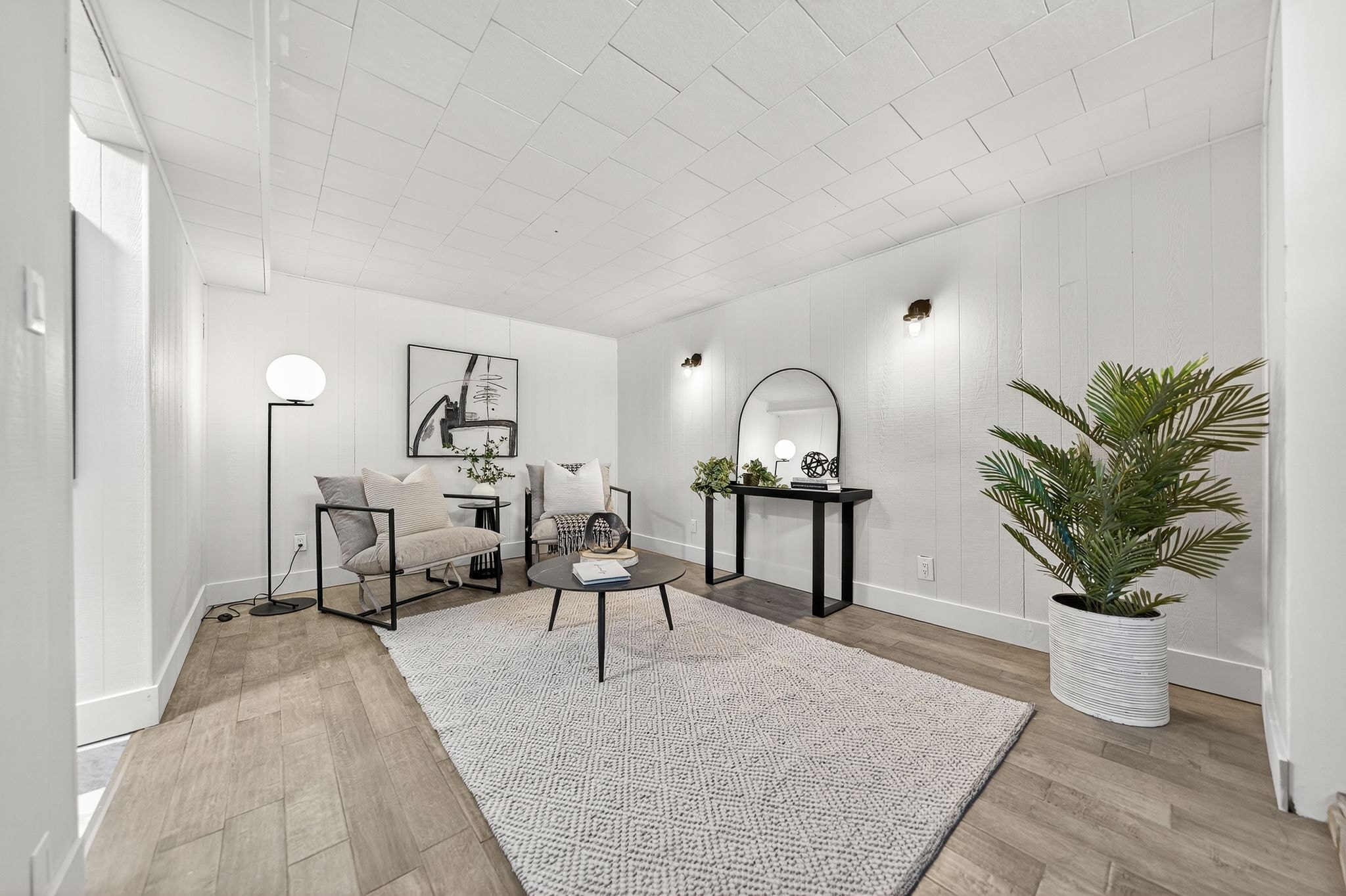Cambridge house refresh — finished basement living space with shiplap walls, new LVP flooring and sconce lighting