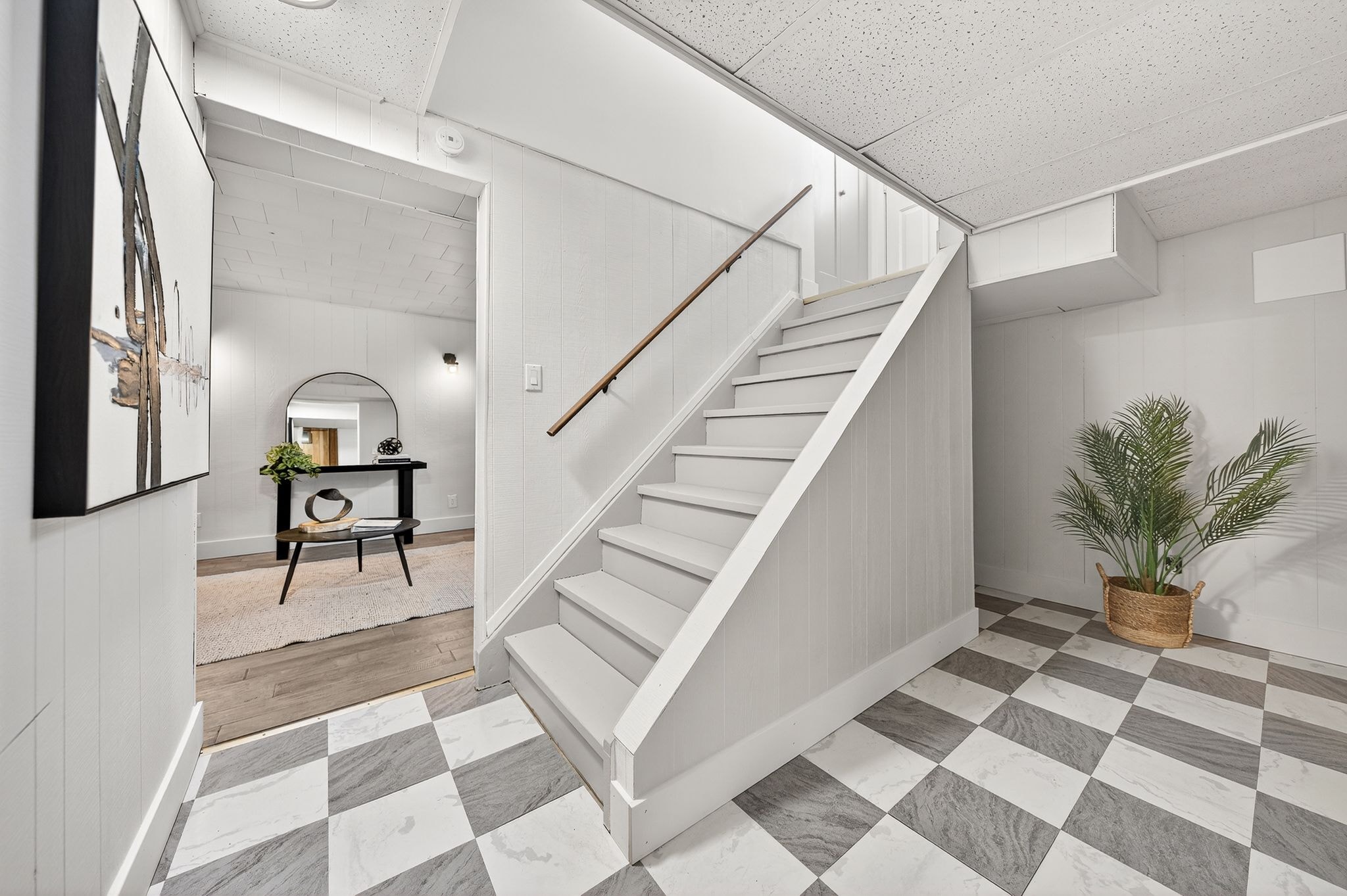 Cambridge house refresh — finished basement staircase with checkerboard tile, shiplap walls and arched mirror