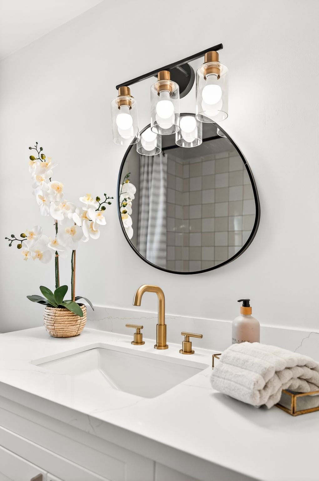 Cambridge house refresh — bathroom vanity detail showing quartz countertop, undermount sink, brushed gold faucet and glass pendant light bar