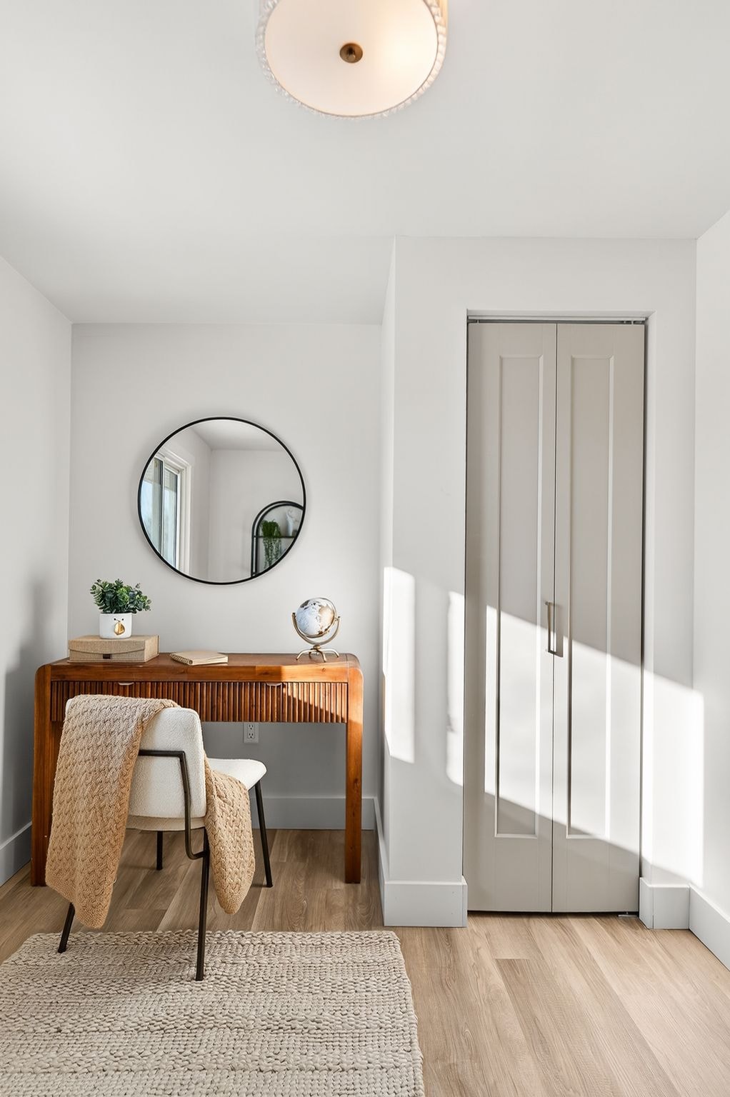 Cambridge house refresh — second bedroom with new LVP flooring, updated closet doors, round mirror and flush mount light