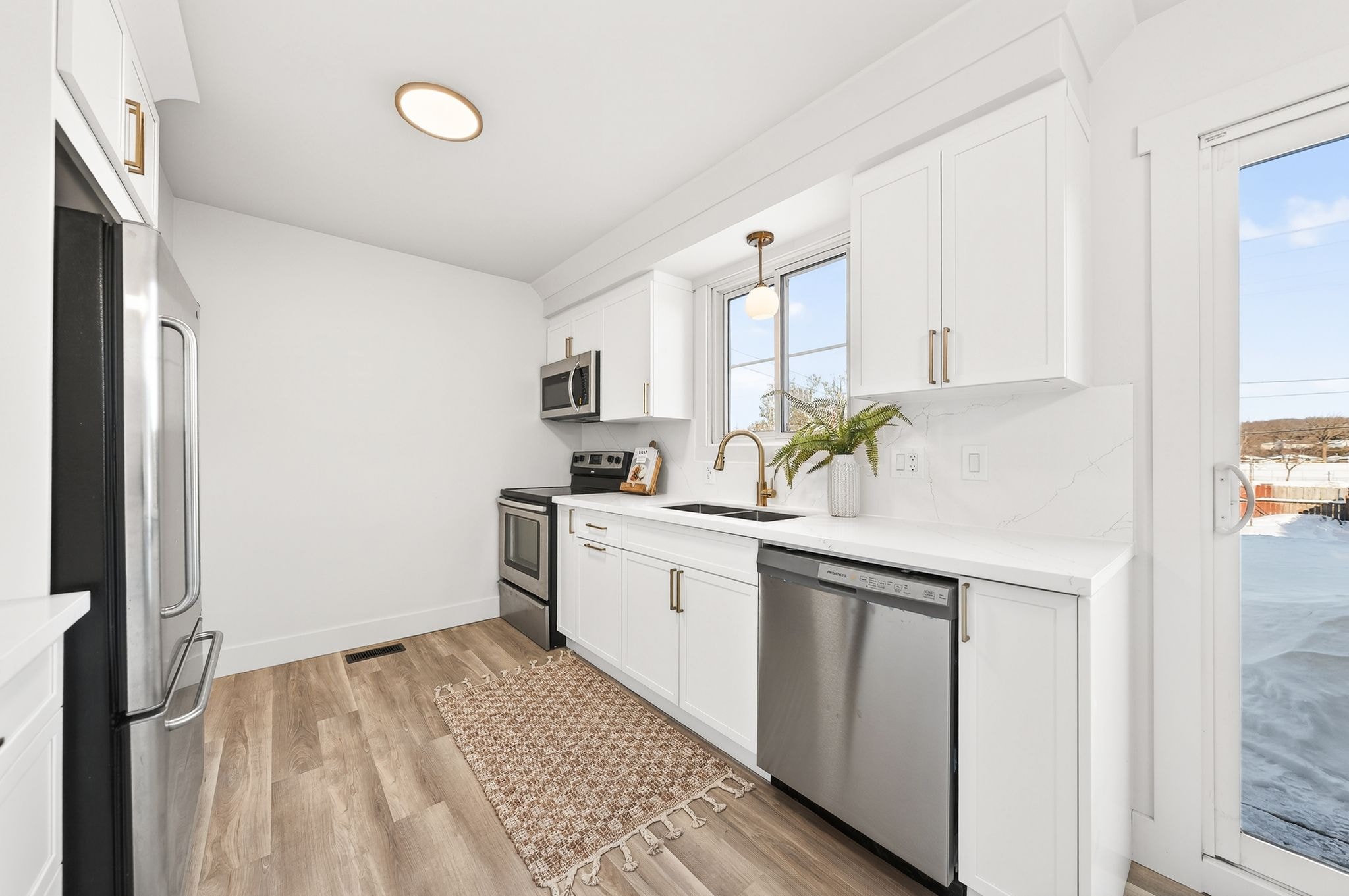 Cambridge kitchen renovation — galley kitchen with white shaker cabinets, quartz countertops, marble backsplash, gold faucet and stainless appliances