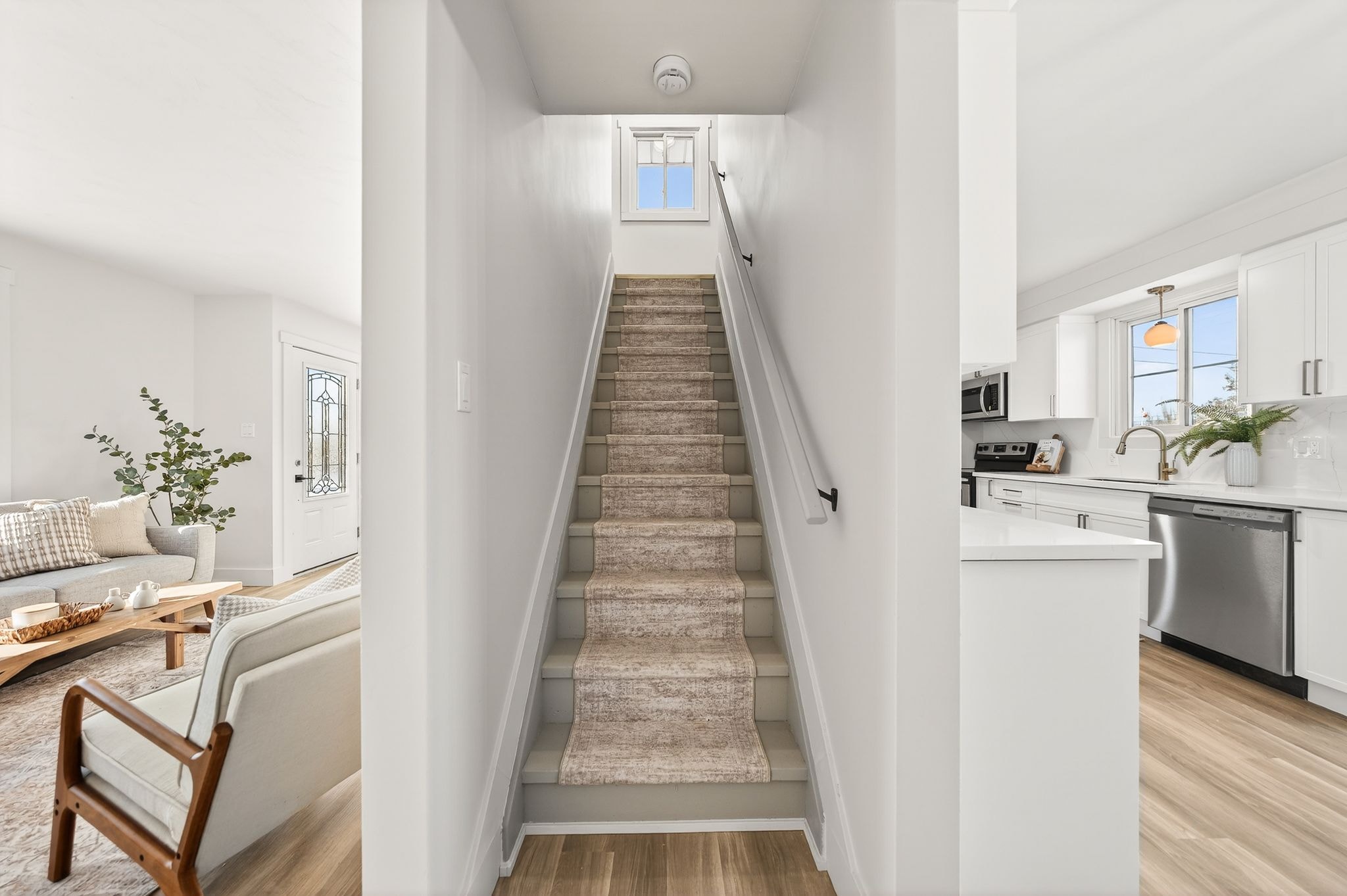 Cambridge house refresh — main floor staircase with updated millwork, new LVP flooring, living room and kitchen visible