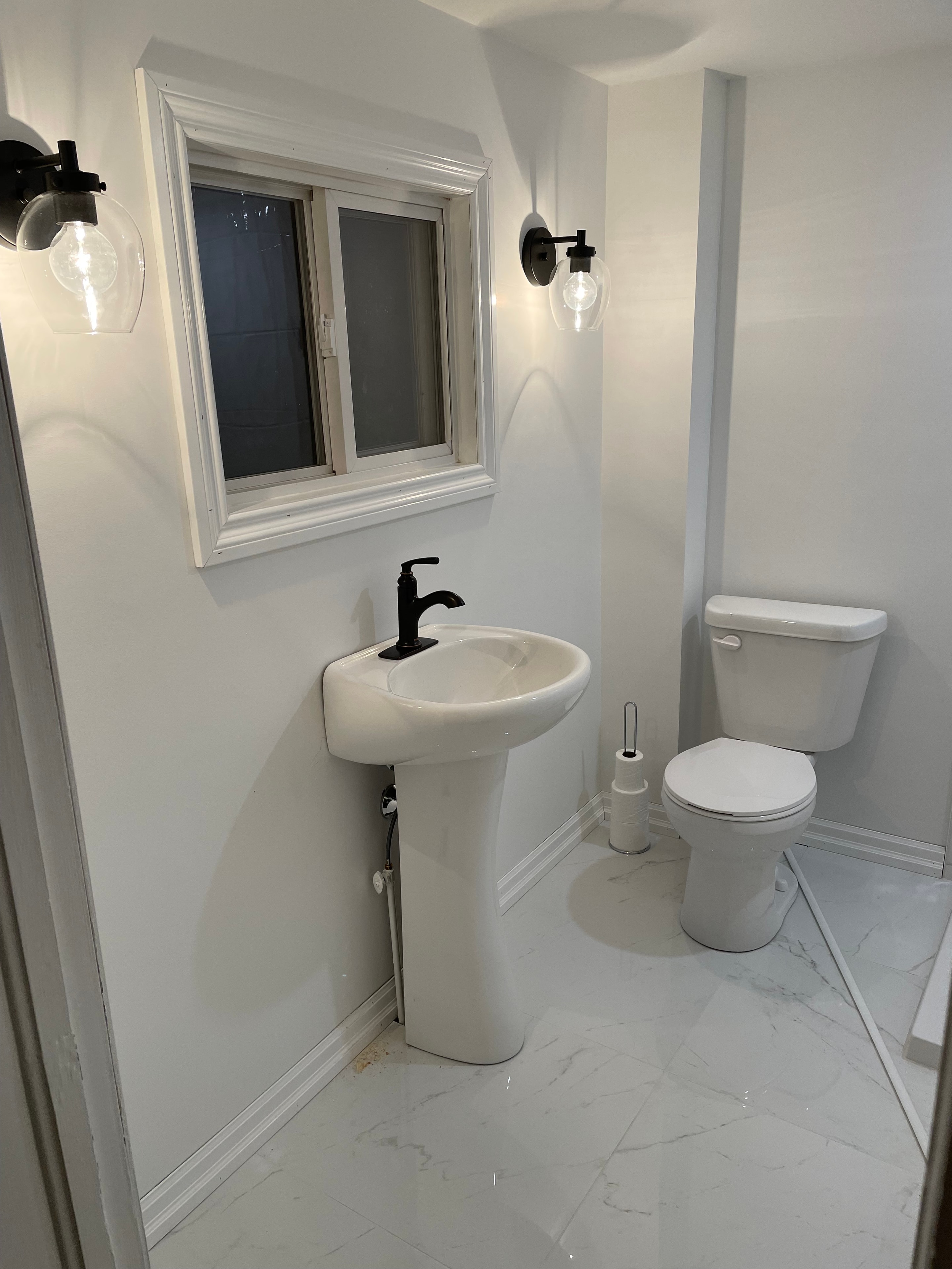 Paris ensuite after renovation — completed bathroom with marble tile and matte black fixtures