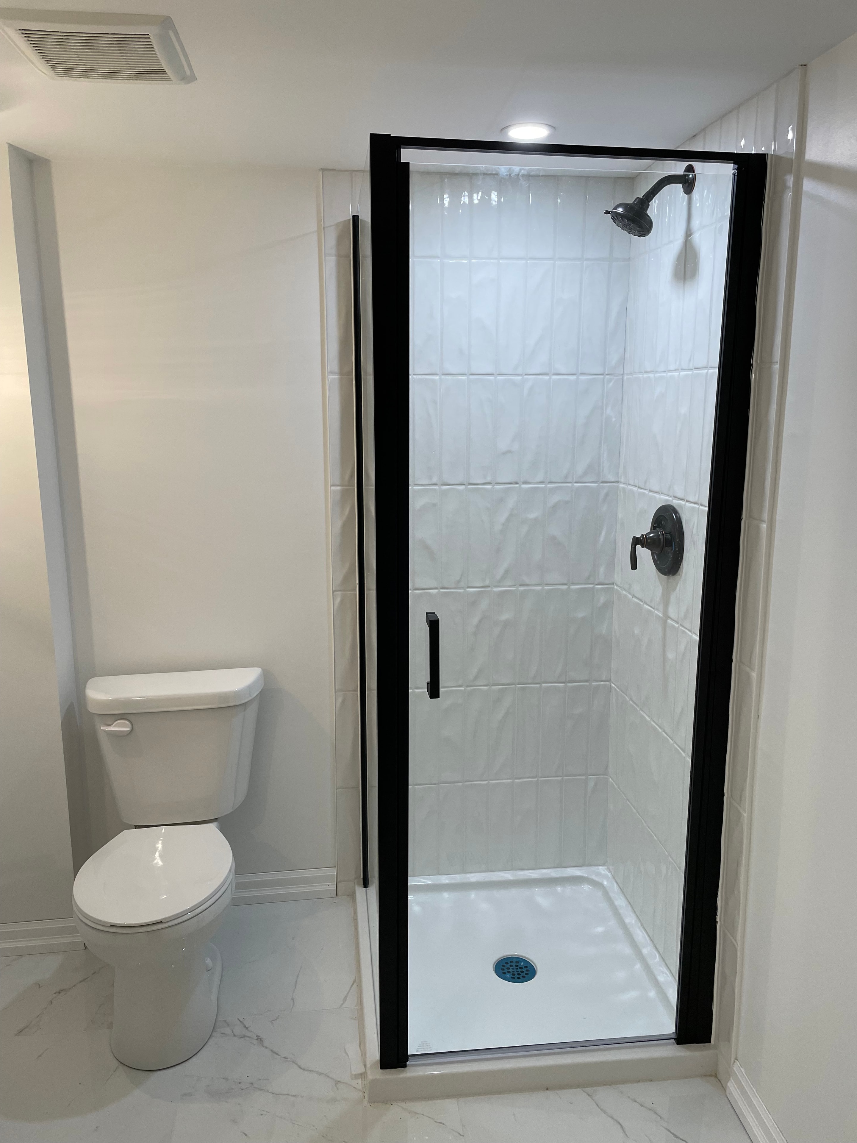 Paris ensuite after renovation — glass shower enclosure with black frame and tile surround